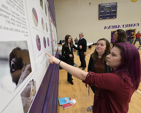 Students reviewing their work at an undergraduate research forum
